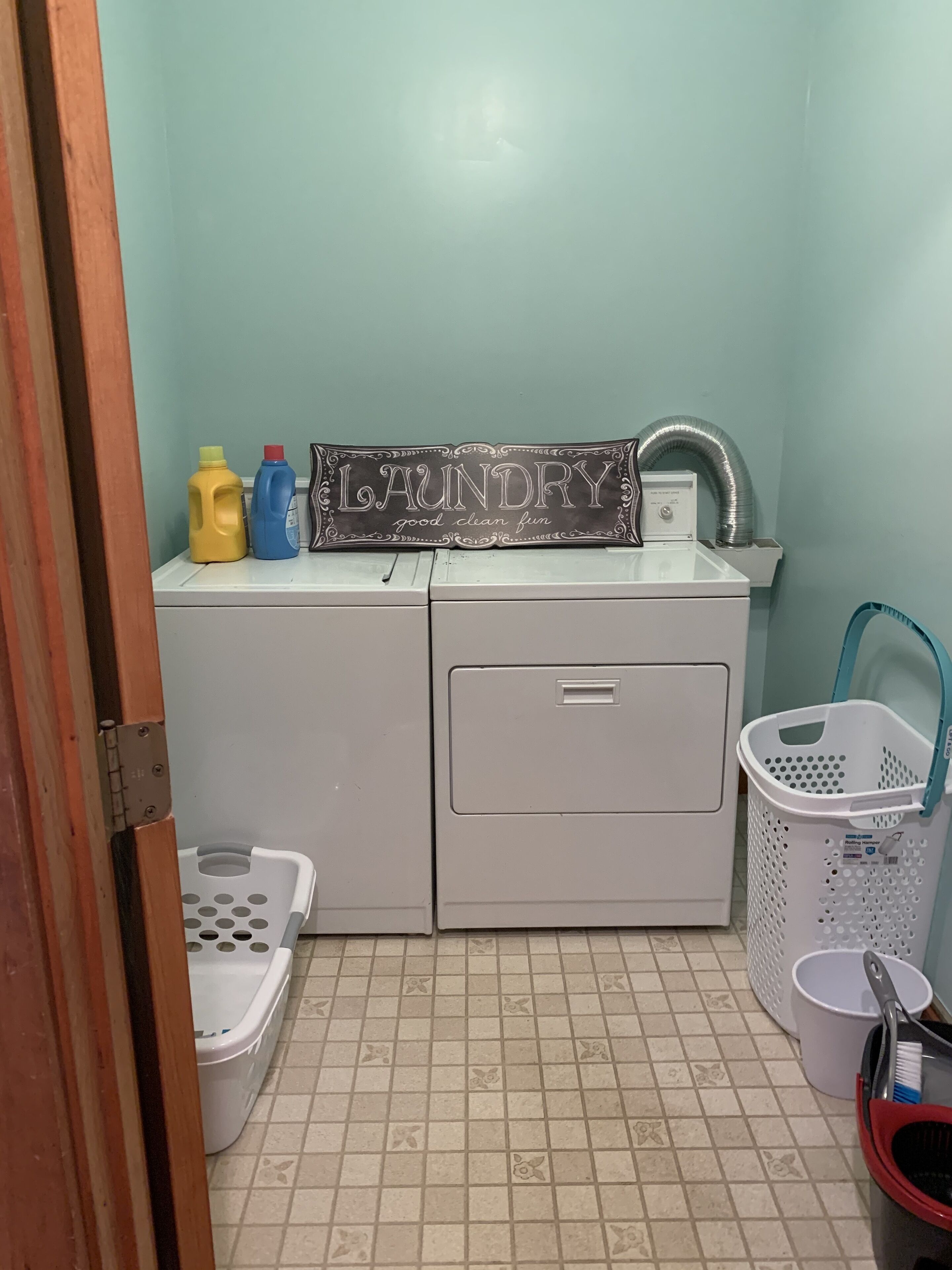 A laundry area with a washing machine, a dryer, and a laundry sign.