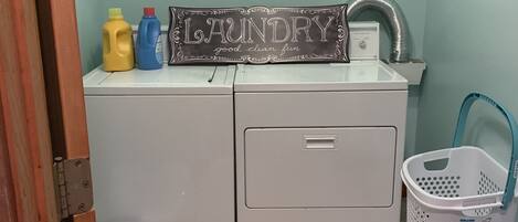A laundry area with a washing machine, a dryer, and a laundry sign.