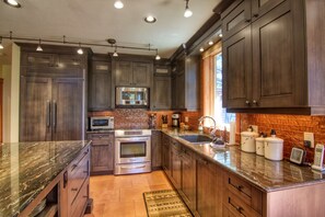 A modern kitchen with dark wood cabinets, stainless steel appliances, and a granite countertop.