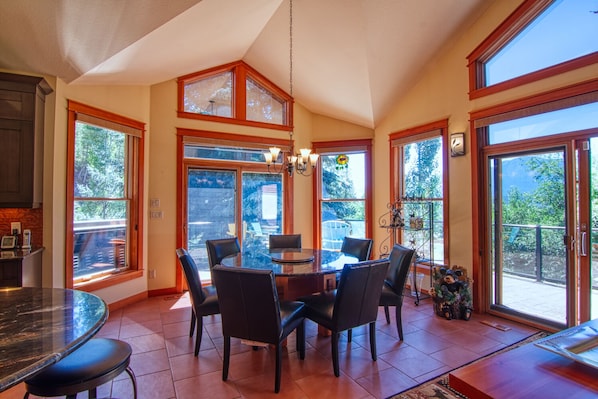 A spacious kitchen with a large dining table and chairs, large windows, and a view of the outdoors.