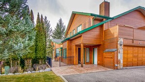 Ein zweistöckiges Holzhaus mit Garage, umgeben von Bäumen.