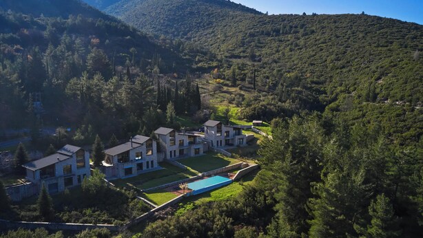 A modern resort with multiple buildings, a swimming pool, and lush surrounding forest.