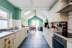 A kitchen with a central island, a dining area, and a view of the outdoors.