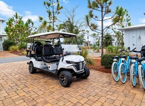 Une voiturette de golf est garée sur une allée pavée, avec une rangée de vélos à côté.