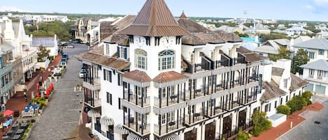 A historic building with a prominent clock tower, multiple balconies, and a central courtyard with outdoor seating.