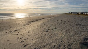 A beach with footprints, a fence, and buildings in the background. - BEACH PLEASE │ 2BR/2BA w/ 2 K in the heart of OKI! (Oak Island)