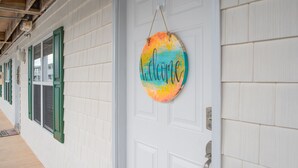 A hallway with white tiled walls and green window shutters. - BEACH PLEASE │ 2BR/2BA w/ 2 K in the heart of OKI! (Oak Island)