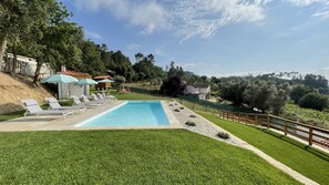 A swimming pool with lounge chairs, a small building with a tiled roof, and a fenced area with trees. - Tower House (Lapela)
