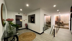 A modern interior with a glass table, a woven rug, and a painting of a castle on the wall. - Tower House (Lapela)