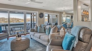 A spacious living room with a large sofa set, a coffee table, and a dining area in the background.