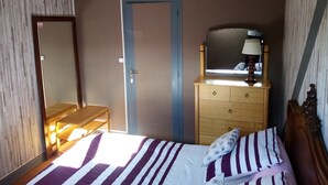 A bedroom with a bed, a dresser, a mirror, and a door. - Waterfront Apartment in Garennes-sur-Eure at Le Havre de Paix - Sleeps 3–4  (Neuilly)
