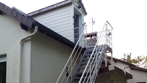 A residential building with a metal stairway leading to a second-floor window. - Waterfront Apartment in Garennes-sur-Eure at Le Havre de Paix - Sleeps 3–4  (Neuilly)