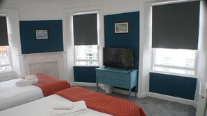 A hotel room with two beds, a television, and a dresser. - En Suite Rooms at the Rose and Thistle (Berwick-upon-Tweed)