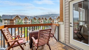 Ein Balkon mit Holzkufen und Tisch, mit Blick auf eine Reihe von Gebäuden und einem Berg im Hintergrund.