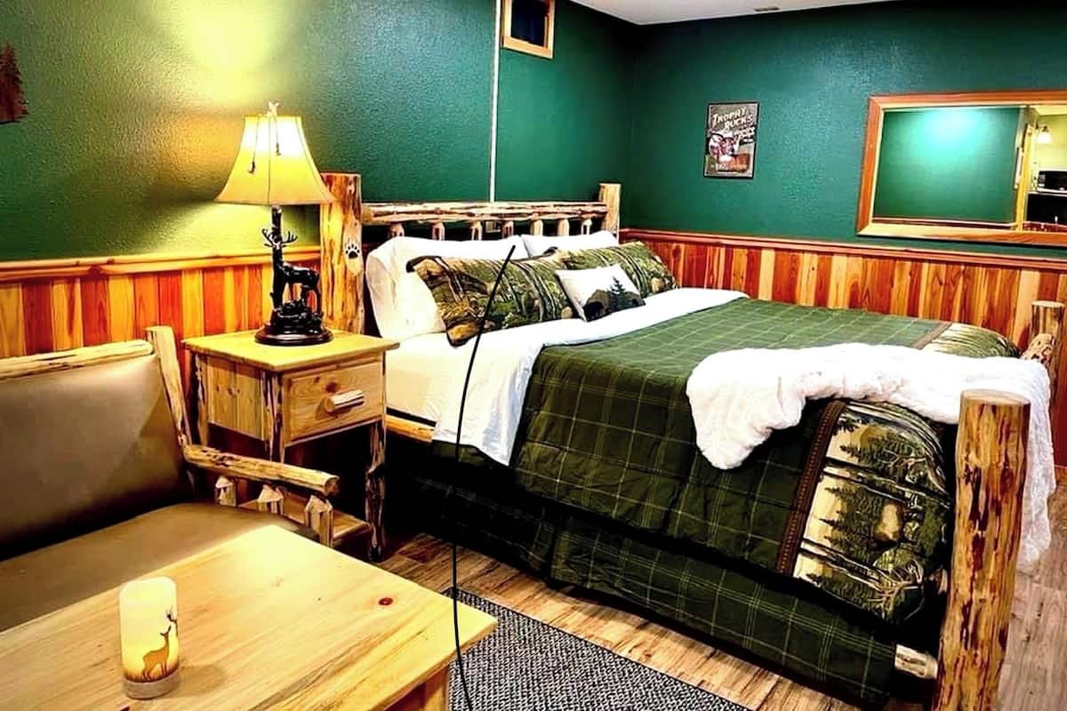 A room with a bed, a nightstand, a lamp, a chair, and a small table.