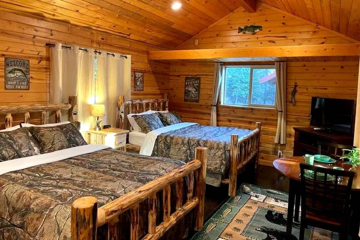 A cabin with two wooden beds, a ceiling fan, a window, and a television.