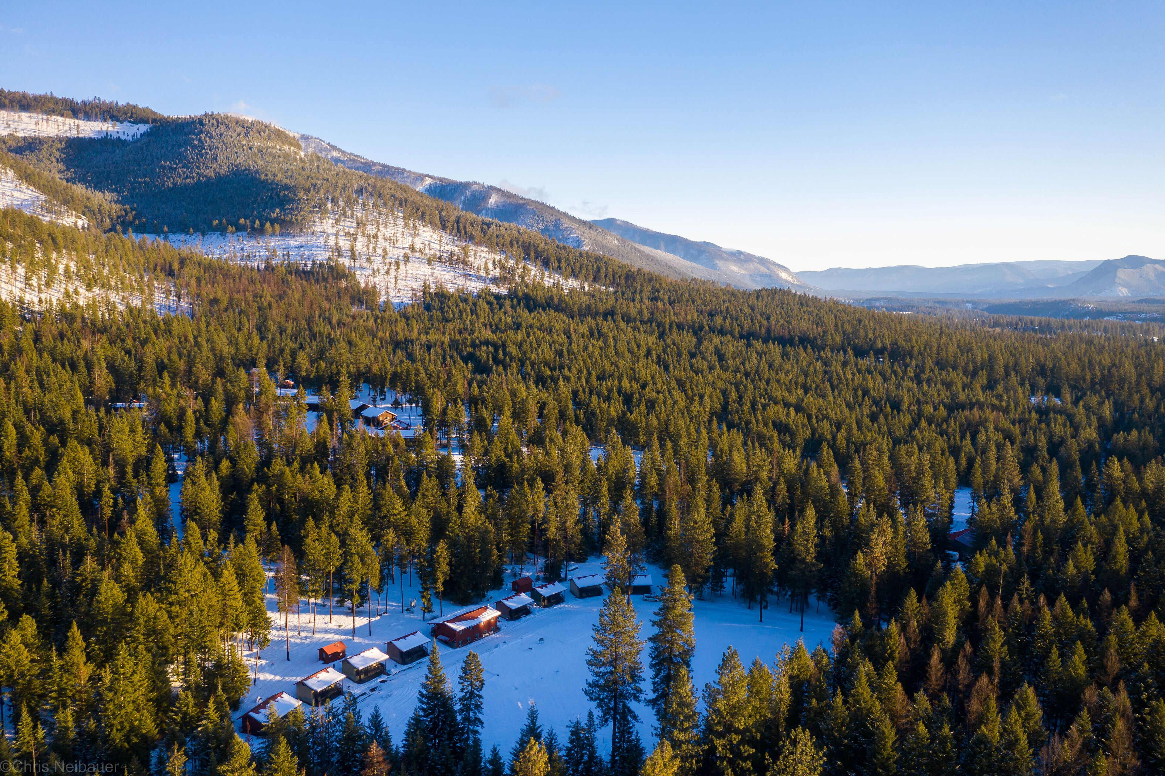 Vue aérienne d’une zone boisée avec des cabanes et un petit lac.