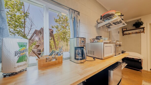 Una cucina con un piano di lavoro in legno, una macchina da caffè, un forno a microonde e un frigorifero.