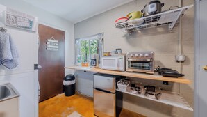 Una cucina compatta con frigorifero, microonde, forno e un piccolo lavandino.