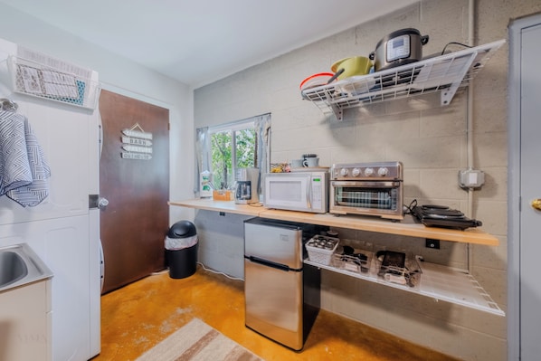 Una cocina compacta equipada con refrigerador, microondas, horno y un lavamanos pequeño.