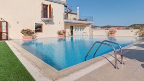A swimming pool with a metal ladder, a building with a balcony, and a clear sky. - Appartamenti Le Fontane con piscina (Villasimius)
