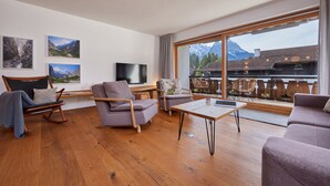 A spacious living room with wooden flooring, a large window with a mountain view, and modern furniture. - WunderSchön - cosy holiday flat with modern design and alpine charm (Garmisch-Partenkirchen)