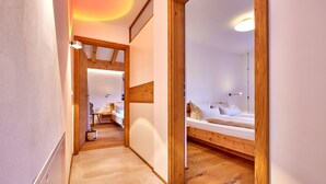 A narrow hallway leading to a bedroom with a wooden bed frame and a bedside table. - WunderSchön - cosy holiday flat with modern design and alpine charm (Garmisch-Partenkirchen)