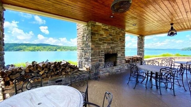 Une terrasse extérieure avec des murs en pierre, une cheminée, ainsi qu’une table et des chaises.