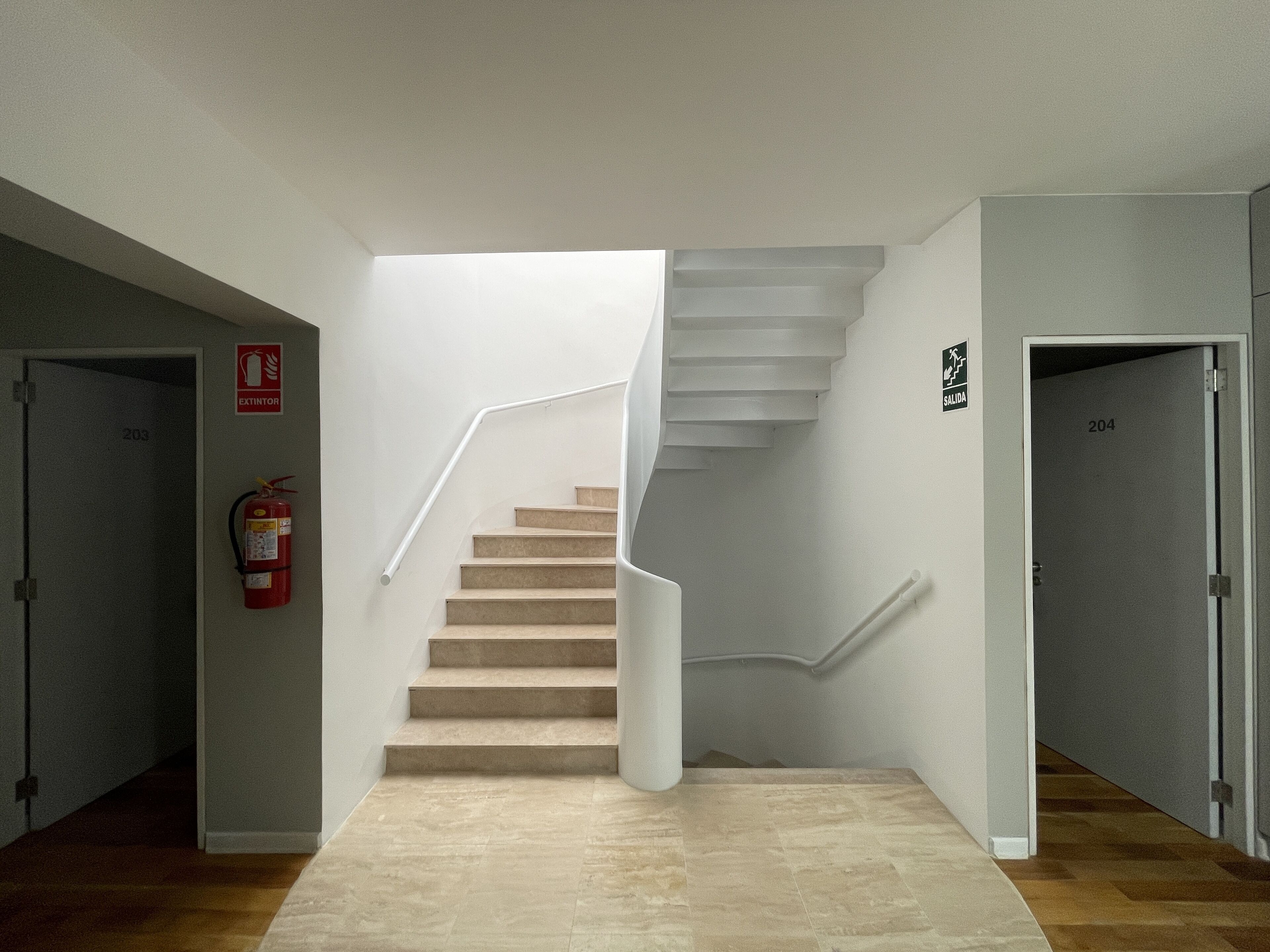 A modern interior with a spiral staircase, a fire extinguisher, and a door labeled "204".