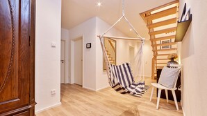 Habitació amb una cadira penjant, un armari de fusta i una escala.