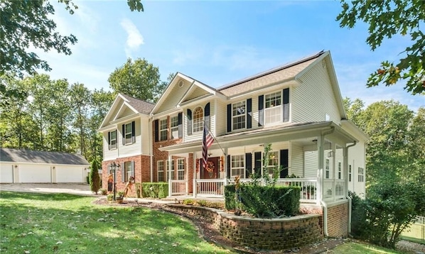 A two-story house with a front porch, a garage, and a well-maintained lawn.