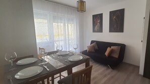 Spiseplads med et bord dækket til to, en sofa og to billeder.