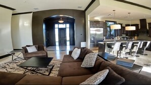 A spacious living area with a brown sofa set, a coffee table, and a dining area with a bar. - Luxury Water Front Villa Freeport Bahamas (Freeport)