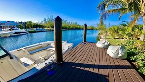 A wooden dock with a boat, a clear blue sky, and a marina with other boats in the background. - Luxury Water Front Villa Freeport Bahamas (Freeport)
