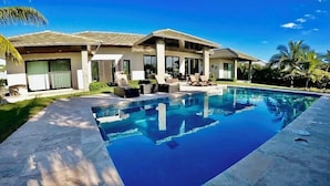 A modern house with a swimming pool, large windows, and a covered patio area. - Luxury Water Front Villa Freeport Bahamas (Freeport)