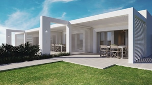 A modern building with a covered outdoor area, featuring multiple seating arrangements and a well-maintained lawn. - Capo Falcone Charming Apartments (Stintino)