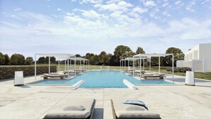 A pool area with two sun loungers, a covered seating area, and a stone wall in the background. - Capo Falcone Charming Apartments (Stintino)