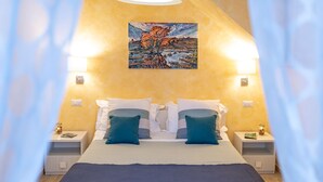 A bedroom with a bed, pillows, bedside tables, and a painting on the wall. - Quirino's House Taormina Center (Taormina)