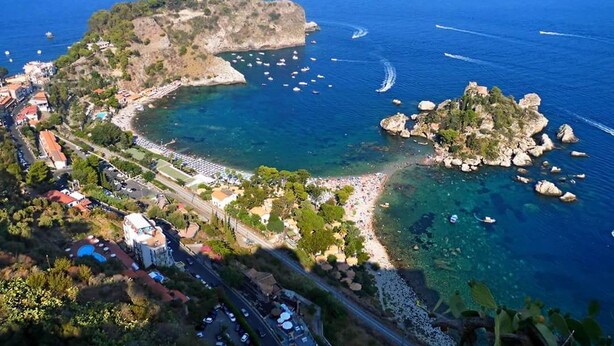 An aerial view of a coastal area with a beach, rocky outcrops, and boats. - Quirino's House Taormina Center (Taormina)