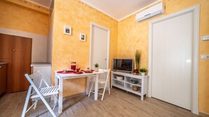 A compact living space with a kitchen, dining area, and a TV. - Quirino's House Taormina Center (Taormina)