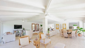 Un vaste espace de vie doté d’un haut plafond, de murs blancs et d’un assortiment de sièges, notamment des canapés et des fauteuils.