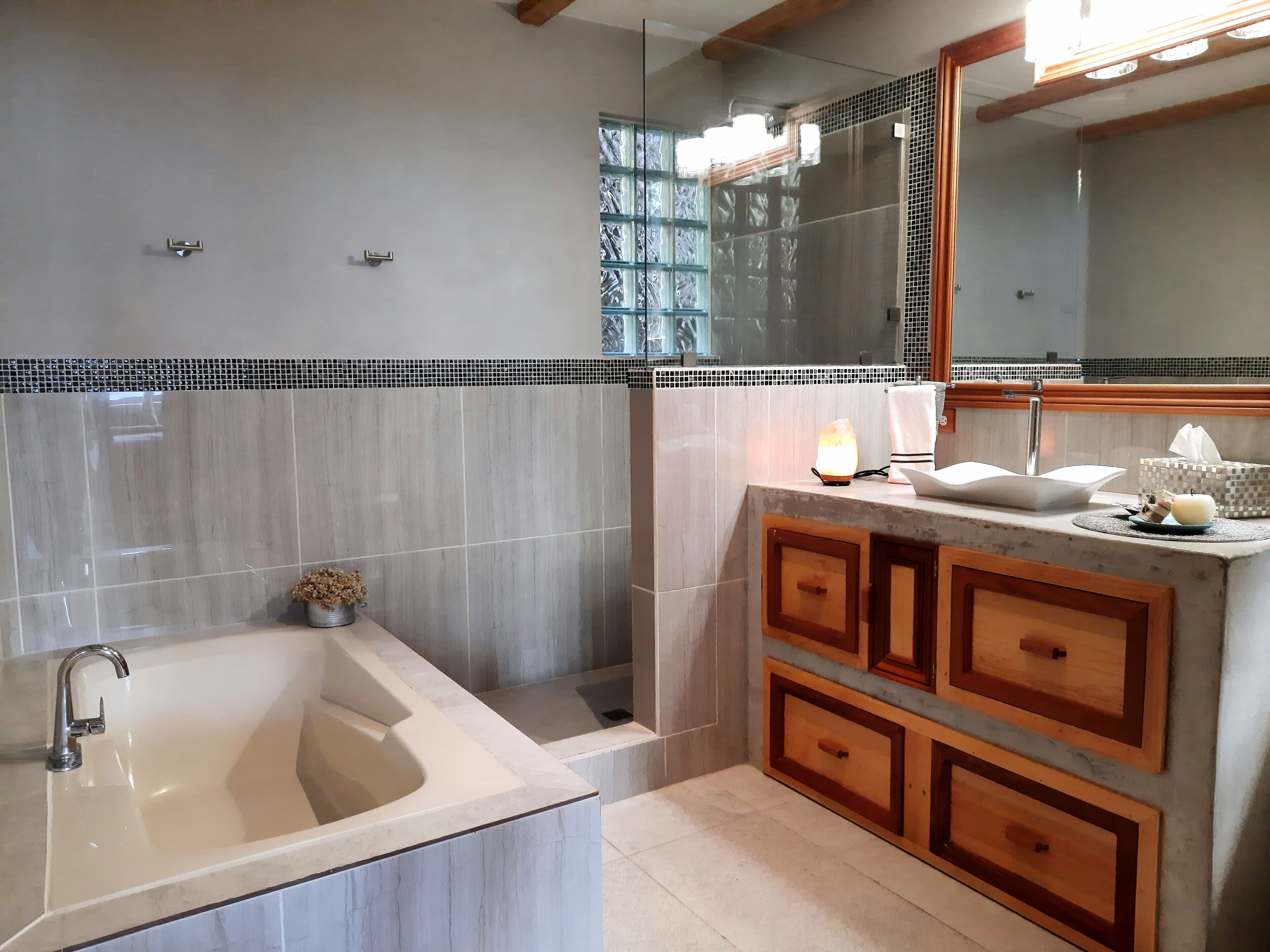 Une salle de bain moderne dotée d’une grande baignoire, d’une cabine de douche en verre et de meubles en bois.