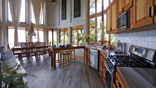 Un'ampia cucina con mobili in legno, piano cottura in acciaio inossidabile e una grande isola con sgabelli.