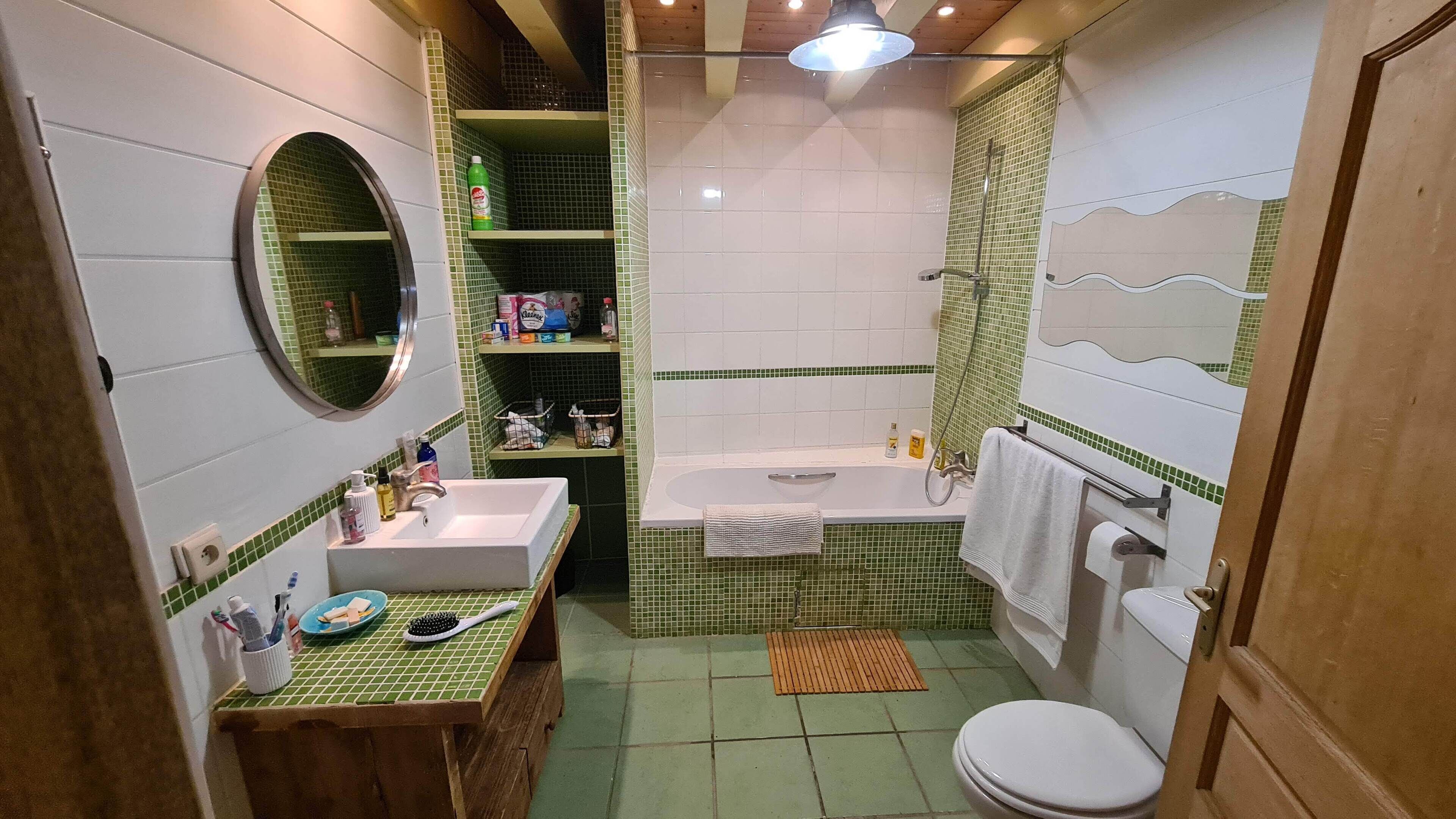 Ein Badezimmer mit Waschbecken, Spiegel, Toilette und Badewanne.