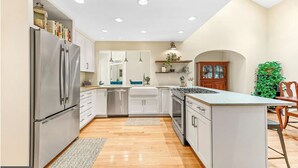 A modern kitchen with white cabinets, stainless steel appliances, and a central island. - Discover tranquility near Calvert Cliffs  (Saint Leonard)