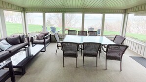A covered patio with a table and chairs, a sofa, and a view of the outdoors. - Private Waterfront Belle Point Shores Cottages (Leamington)