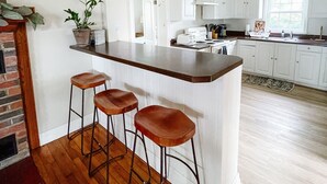 A kitchen with a bar area, wooden flooring, white cabinets, and a potted plant. - Private Waterfront Belle Point Shores Cottages (Leamington)