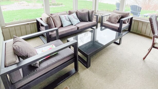 A covered outdoor seating area with a sofa, chairs, and a coffee table. - Private Waterfront Belle Point Shores Cottages (Leamington)