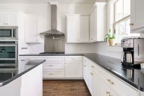 Een moderne keuken met witte kasten, roestvrijstalen apparatuur en een zwart aanrecht.
