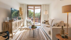 Een moderne woonkamer met een bank, een salontafel, een televisie en een balkon met tuinmeubilair.